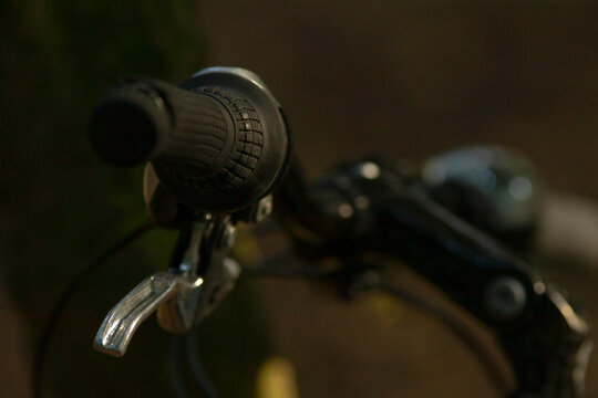 A detailed close-up view of a bicycle handlebar featuring a textured grip and a shiny brake lever, showcasing the mechanics of cycling gear.