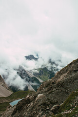 Hochalpiner Bergsee umgeben von dramatischer Felslandschaft und Nebelschwaden