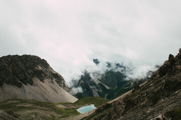 Hochalpiner Bergsee umgeben von dramatischer Felslandschaft und Nebelschwaden