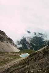 Hochalpiner Bergsee umgeben von dramatischer Felslandschaft und Nebelschwaden