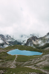 Hochalpiner Bergsee umgeben von dramatischer Felslandschaft und Nebelschwaden