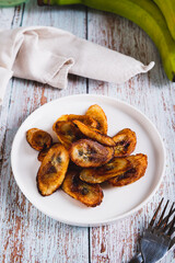 Tajadas fried banana on a plate on the table vertical view