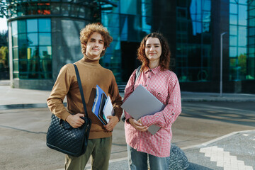 Academic students portrait holding books outside modern glass building