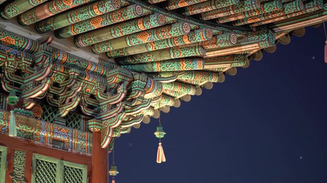 Intricate Details of a Traditional Korean Palace Roof Illuminated at Night with Hanging Lanterns.