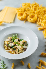 Fusilli pasta with parmesan cheese and arugula on white plate