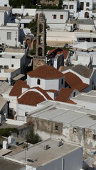 Traditional mediterranean town with whitewashed buildings, red tiled domes and a stone bell tower. Lindos 
