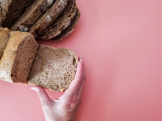 Hand holding a slice of bread on a pink surface