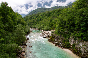 Photography of the Soča River in Slovenia, showing turquoise water, rocky riverbanks, surrounding...