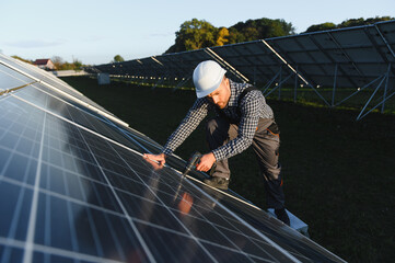 Fototapeta na wymiar Man worker mounting photovoltaic solar panels. Engineer in helmet installing solar module system. Concept of alternative, renewable energy