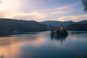 Scenic view of Lake Bled with the Church of the Assumption on Bled Island, surrounded by mountains and forested hills in Slovenia