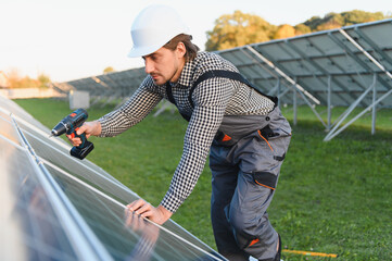 Man worker mounting photovoltaic solar panels. Engineer in helmet installing solar module system....