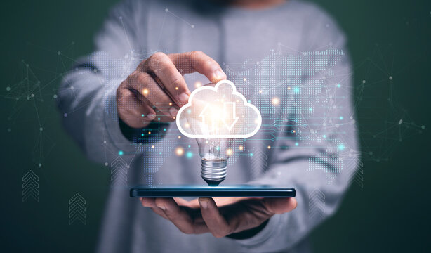 Businessman holding light bulb with cloud computing icon above smartphone. Symbolizing innovation, big data, digital transformation, online storage and modern technology solutions.