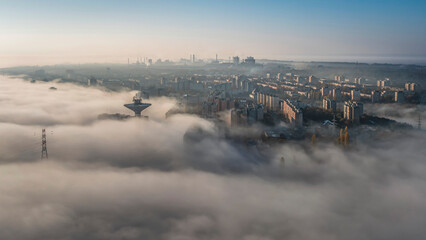 Autumn cityscape wrapped in mist, with modern buildings and industrial skyline emerging...
