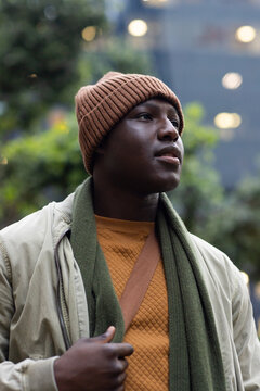 African american man standing in plaza wearing brown beanie and olive scarf