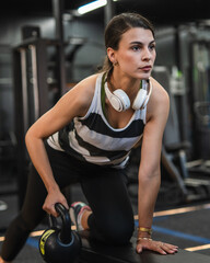 focused adult woman exercise with kettle bell at gym