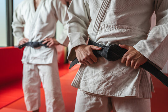 Martial arts athletes adjusting black belt during practice