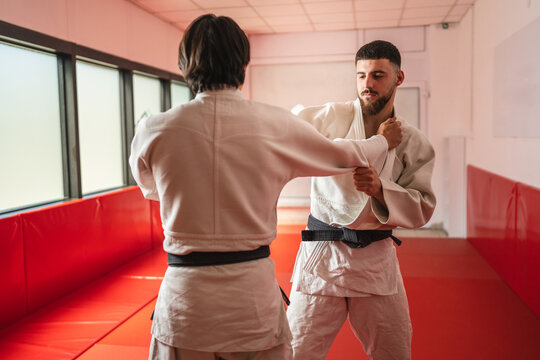Two judo athletes training together in a modern dojo