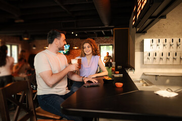 Couple drinking beer and eating snacks at the counter in a pub