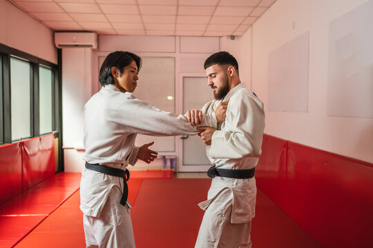 Two martial arts athletes practicing arm lock in gym