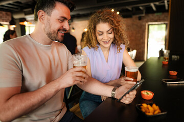 Couple enjoying drinks and social media at the bar counter