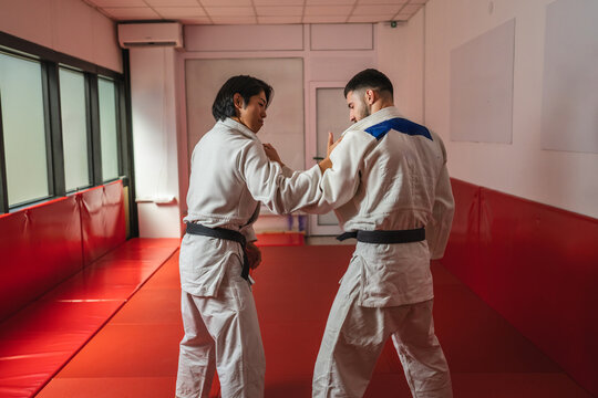 Two judo athletes training together in dojo: practicing martial arts