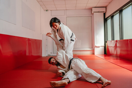 Two martial artists performing a throw on a red mat