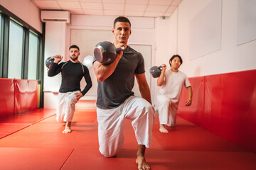 Martial arts athletes lifting kettle bells during functional training in gym
