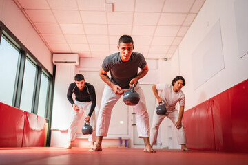 Martial arts athletes lifting kettle bells during training session