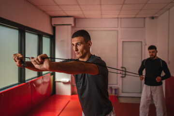 Determined athletes using resistance band during strength training in gym