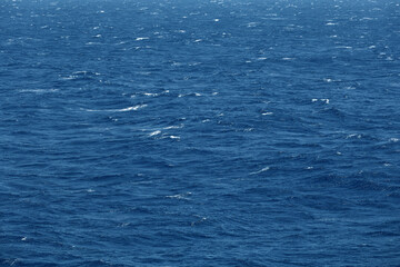 Fototapeta premium Sea surface aerial view. Background shot of clear sea water surface. Blue sea water in calm. Sea texture. Background blue waves of the sea with sea foam.