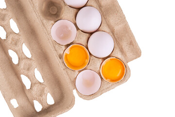 Top view of a cardboard egg carton with whole and cracked eggs showing vibrant yolks on a white background. Ideal image for food blogs, grocery design, or nutrition content.