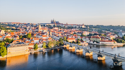 Fototapeta premium The sun rises over Prague, illuminating the medieval architecture and the Vltava River. The Charles Bridge bridges the gap between the city's past and present, creating a breathtaking panorama.