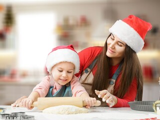 Friendly young mother with little daughter cook at modern kitchen