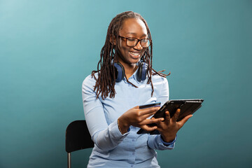 Smiling african american woman using her tablet to make a payment, entering credit card details. Cheerful black female individual sits and completes online transaction with her digital device.