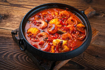 Traditional artisan homemade gambas prawn und fish stew romesco de peix in cast-iron skillet