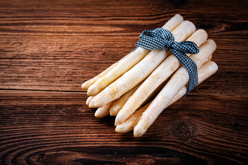 Raw white asparagus bunch offered as bundle on rustic wooden board