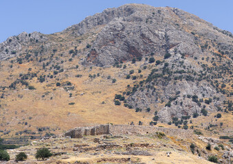 Ancient Mycenean walls as seen from a distance in a barren landscape