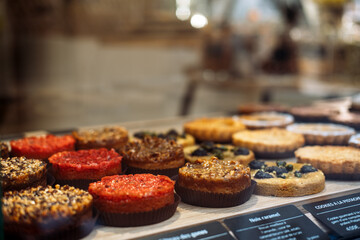 Assorted French pastries with nuts, fruits, and caramel are displayed in a bakery window. Culinary heritage, artisanal craftsmanship, slow food movement, gourmet culture