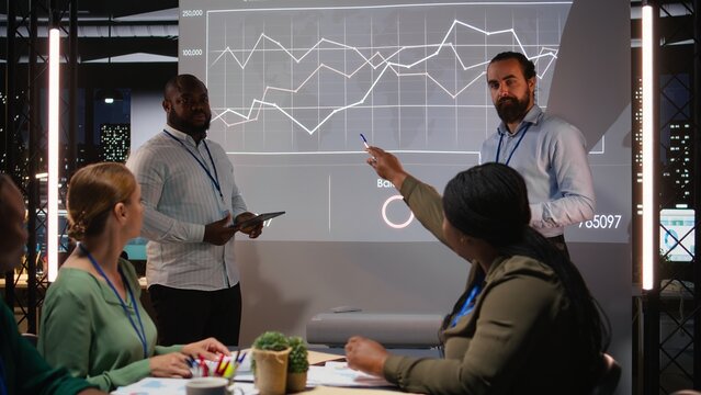 Group of business associates preparing their forecast pitch for a discussion with investors, increasing funds and corporate activity. Experts addressing financial status at night time. Camera A. - Powered by Adobe