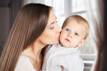 Cheerful smiling mother and cute baby child at home