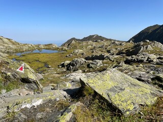Mountain trail marker painted on a rock with a red triangle in a European rocky landscape, guiding...