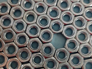 Hex Nuts Array with Missing Piece on Gray Surface CloseUp View.