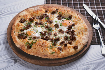 Homemade pizza with meat chunks and egg. Freshly baked meat and egg pizza close up. Gourmet egg and meat topped pizza.