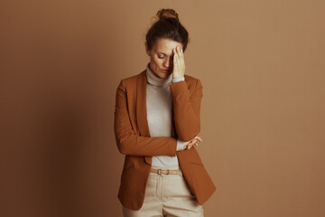 A professional woman, stressed, presses her hand to her forehead, conveying weariness or a...