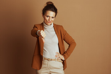 A professional woman in a brown blazer and beige turtleneck expresses disapproval with a...