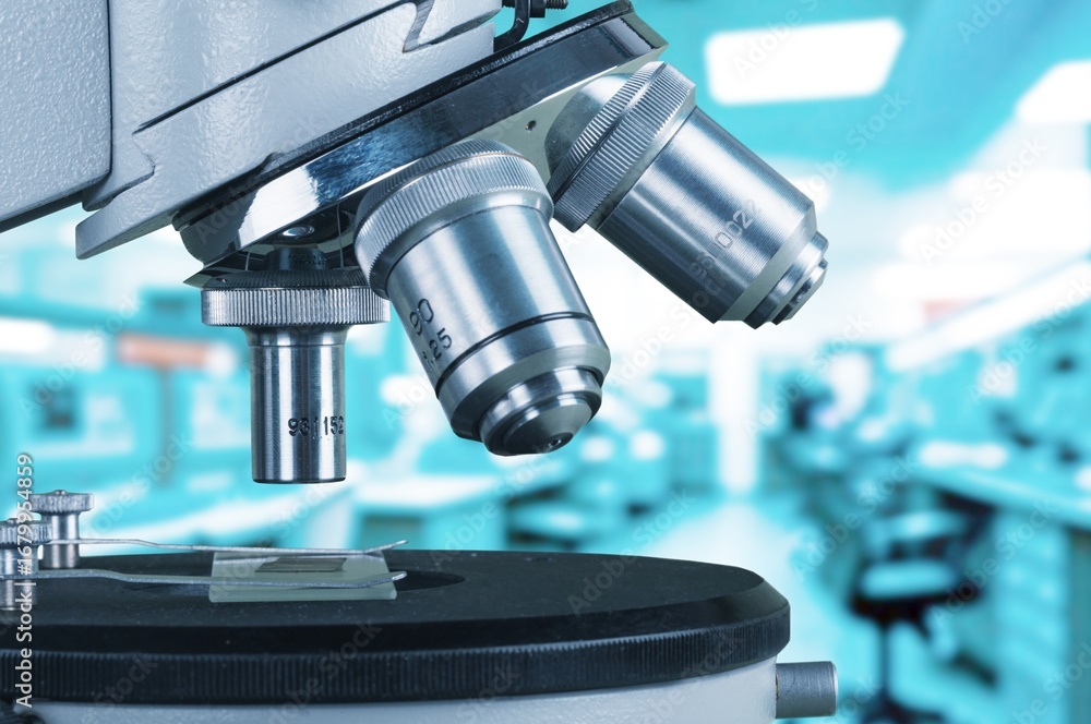 Poster scientist using modern microscope in big laboratory.