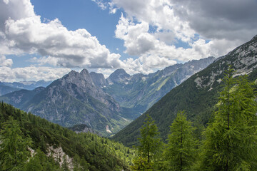 Obraz premium Scenic alpine panorama from Mangart, Slovenia, showing dramatic mountain peaks, rocky ridges and lush valleys under clear blue sky