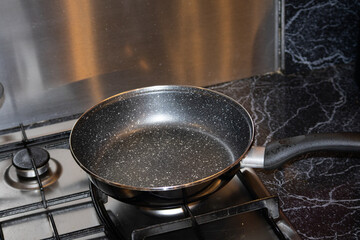 A clean, modern non-stick pan heating up on a gas burner