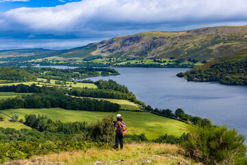 Hiker with backpack photographing the scenic view of Ullswater from Gowbarrow Fell.