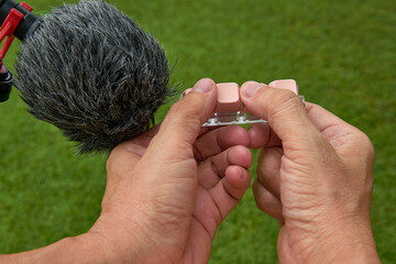 A person's point of view holding a microphone and a mechanical keyboard, recording ASMR sounds outdoors.